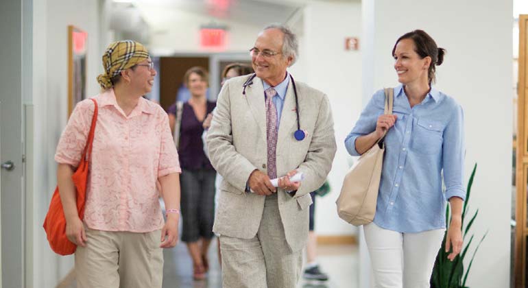 Image of Dr. and patient with caregiver walking together
