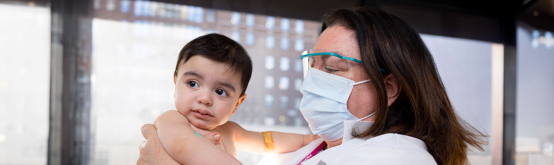 masked doctor lifting baby