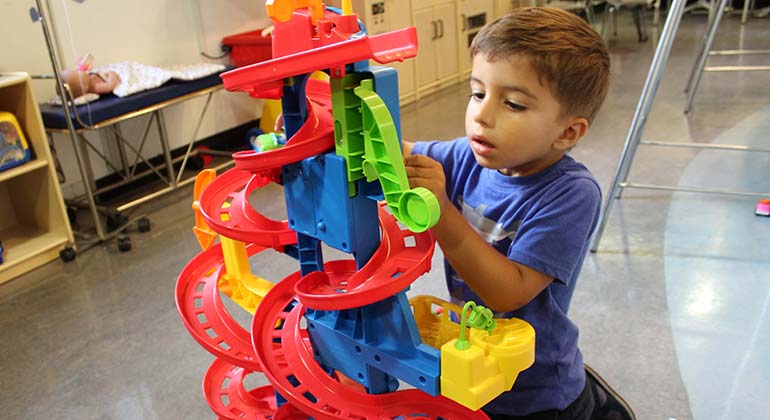 Young male patient plays with toys at the Kravis Children’s Hospital