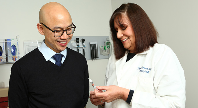 Dr. David Lam and Cynthia Esrig, NP, look at syringe