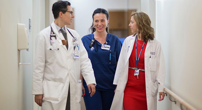 Three physicians walking together in medical hallway