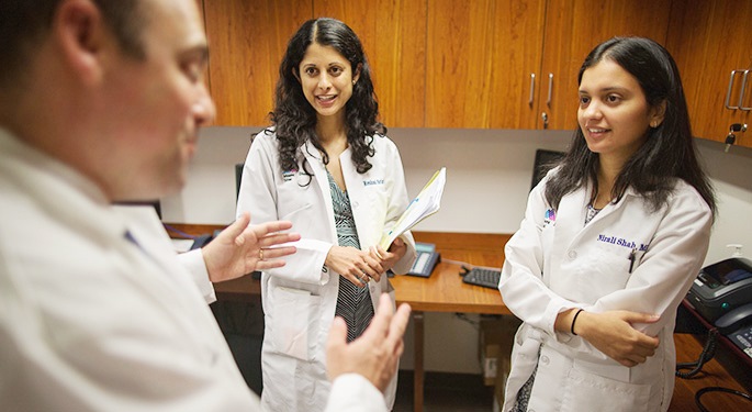 Doctors Tamler, Srinath, and Shah discussing a case in a cabinet-lined space