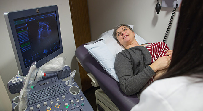 Doctor performing sonogram on pregnant woman