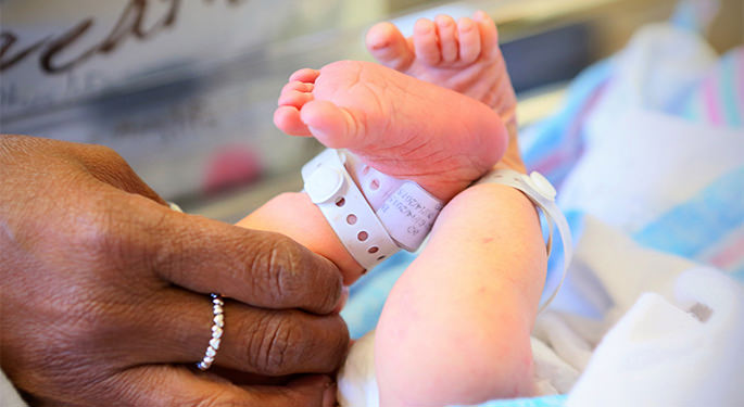 Hand holding newborn baby’s feet