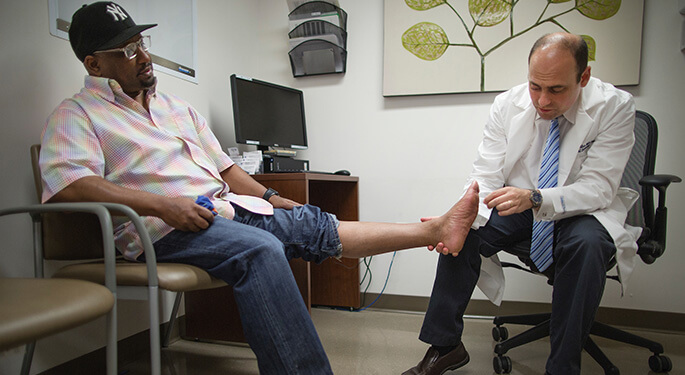Dr. Ronald Tamler examines foot of seated patient