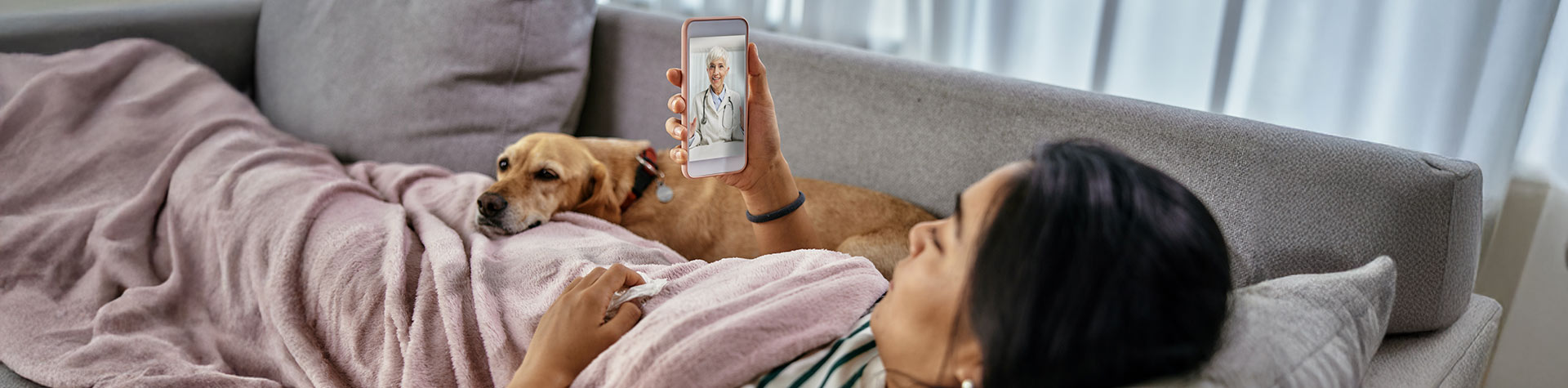 patient with dog on mobile phone with doctor via an On-Demand Virtual Urgent Care Video Visit